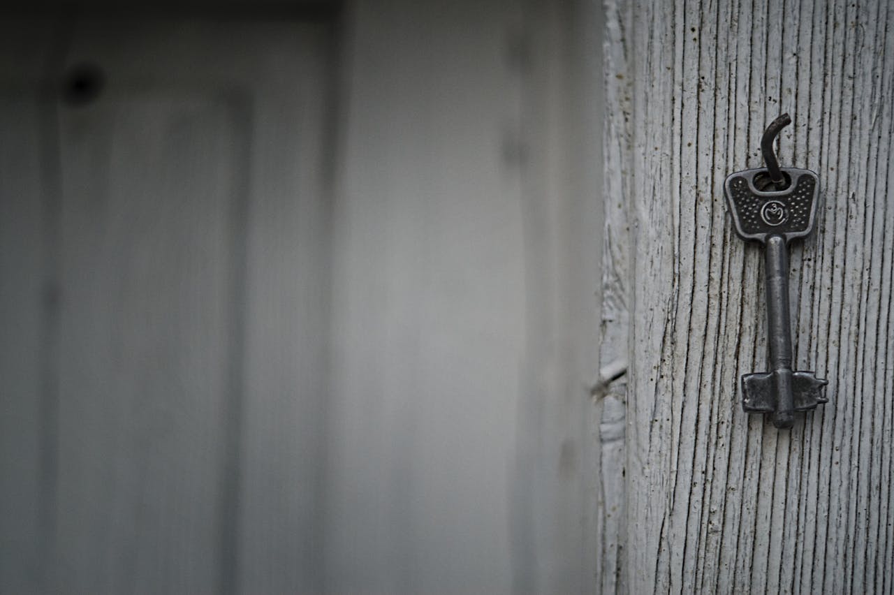 A vintage iron key hangs on a textured weathered wooden wall, evoking nostalgia and mystery.